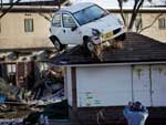 Homem fotografa carro que acabou arrastado para cima de uma casa em Sendai