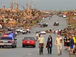 Moradores caminham em rua devastada por tornado na cidade de Joplin