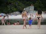 As pessoas caminham pela praia que tem muitas atraes mesmo com chuva 