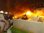 Protegidos por policiais militares, bombeiros tentam apagar o fogo dos banheiros qumicos