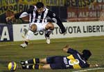 Depois da jogada ofensiva, Roberto Gamarra (acima), do Libertad,  pula para no atingir o jogador Cludio Morel (no cho), do Boca Juniors.