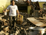 Cenrio impactante em Ica, com casas totalmente destrudas e pessoas recolhendo objetos 