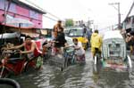 Comerciantes circulam mesmo em rua alagada em Manila, nas Filipinas