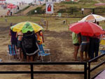 Pblico se protege da chuva na orla da praia em Capo 