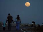 Populao e turistas caminham  luz da lua no molhe de Itaja.