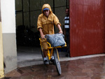 Debaixo de chuva, o carteiro Renan cumpre mais um dia de trabalho.