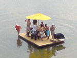 Grupo de Stammtisch em uma balsa com barraca e churrasqueira navegando pelo rio Itaja-a.