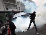 Manifestante joga uma bomba de gs lacrimogneo na polcia durante confrontos no centro de Atenas